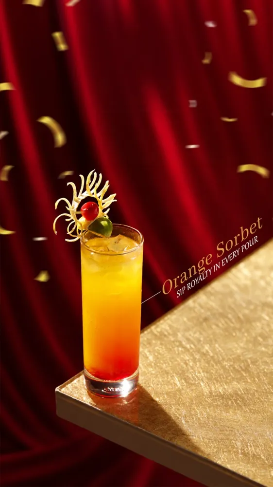 Orange Sorbet mocktail post: a tall orange-to-red drink with citrus garnish against a red velvet curtain
